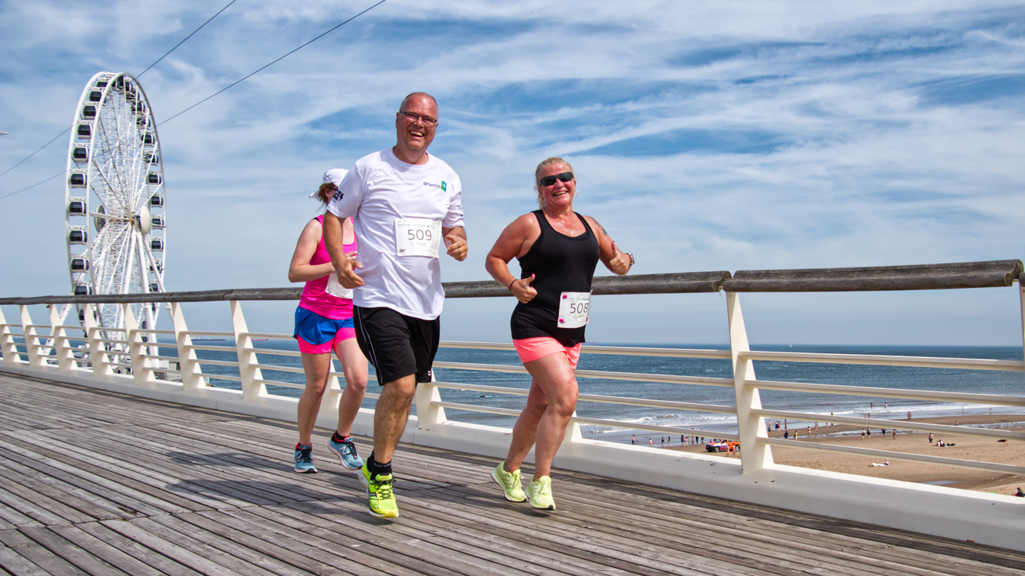 A man and woman running jogging along Scheveningen pier, during the 5k event at the Aramco Beach Run