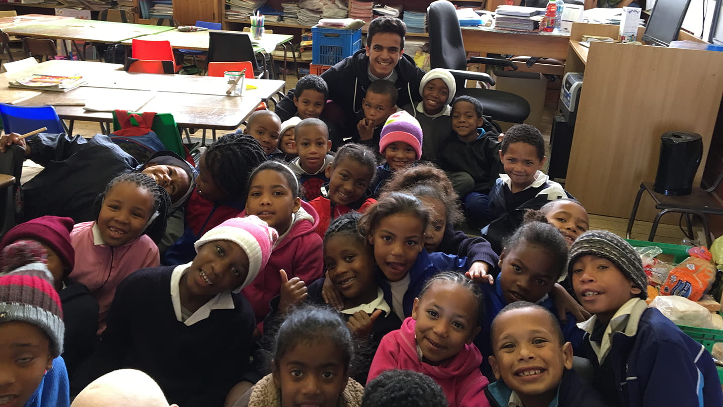 Aramco student Turki together with school children in a classroom in South Africa