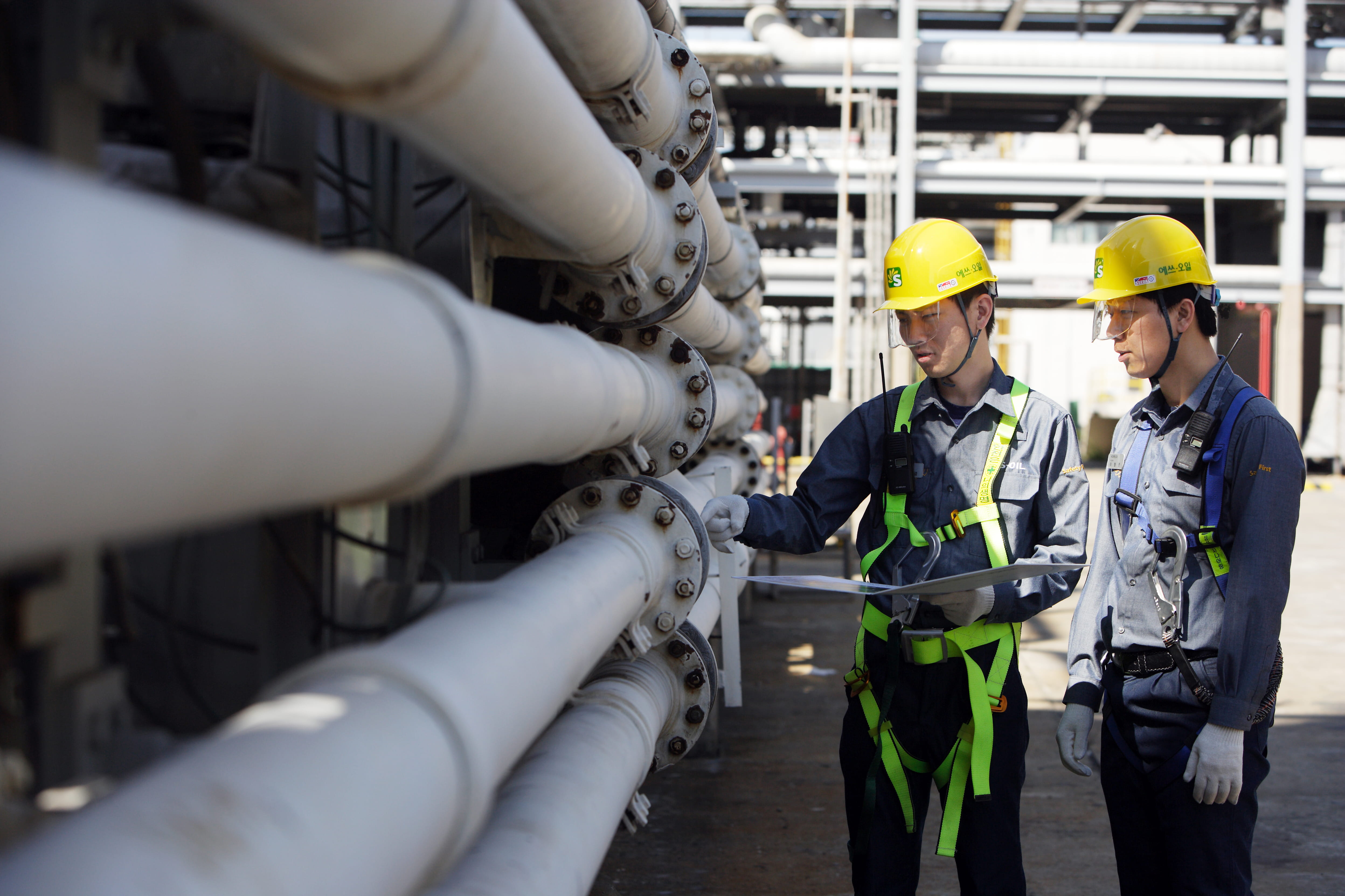 S-Oil workers in safety gear inspecting pipework