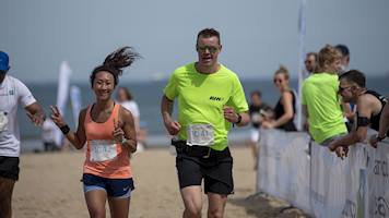 A man and a woman running towards the finish line during the Aramco Beach Run 5k event.